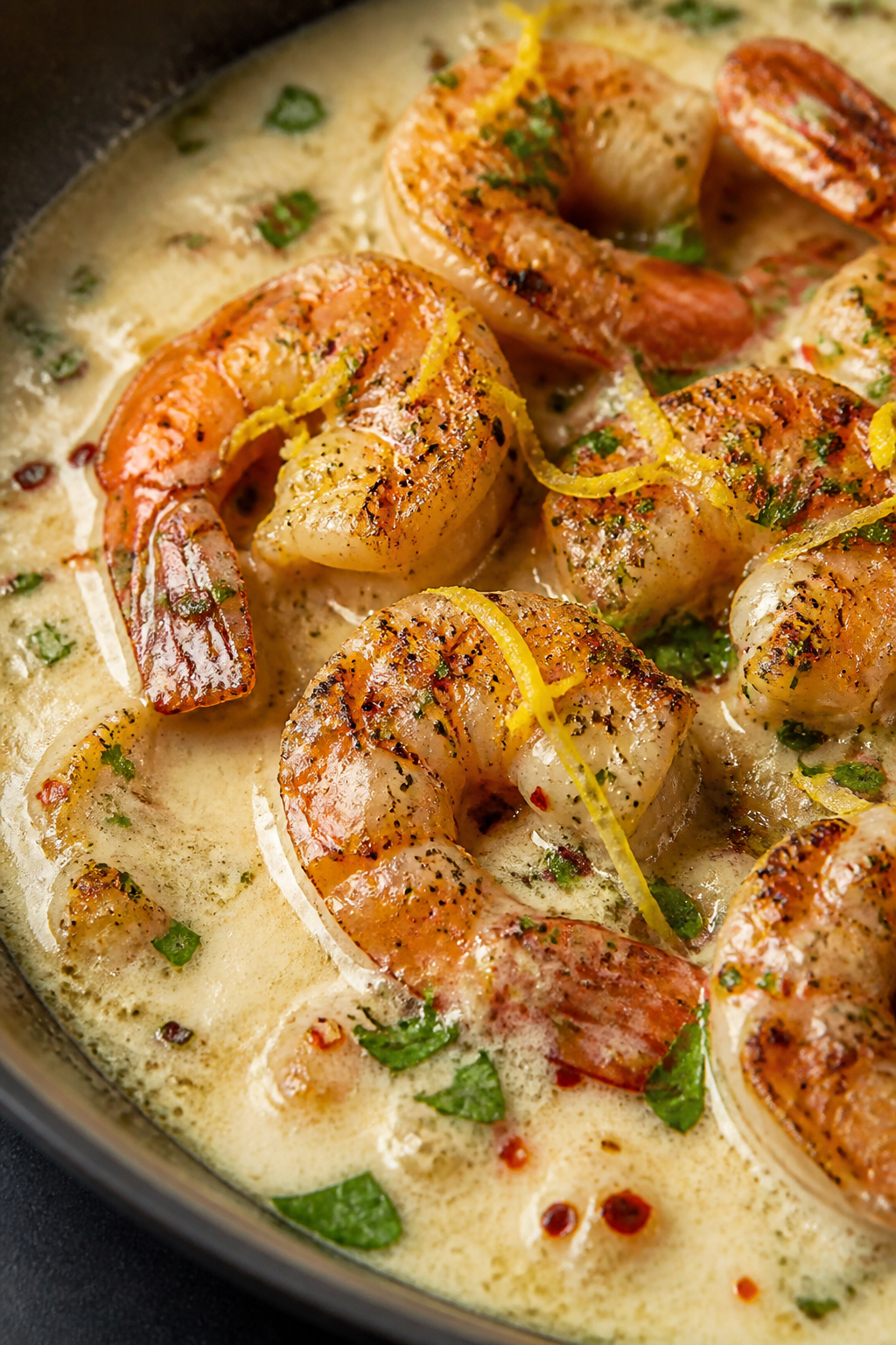 Close-up detail: Golden-seared large shrimp nestled in a silky creamy garlic-Parmesan sauce, tiny re