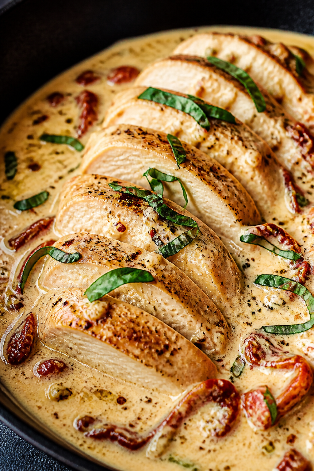 Close-up detail: Sliced seared chicken breast in a skillet nestled in a silky, lightened âMarry Me
