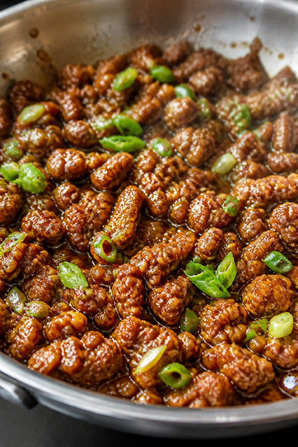 Close-up detail: Sticky honey garlic ground beef sizzling in a stainless-steel skillet right after t