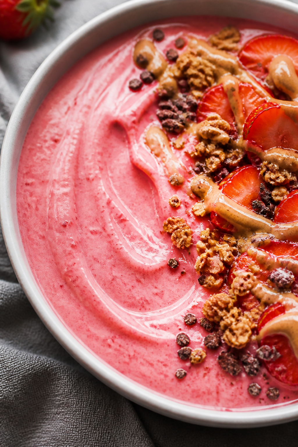 Close-up detail: Thick, creamy strawberry smoothie bowl base just poured into a matte white bowl, su