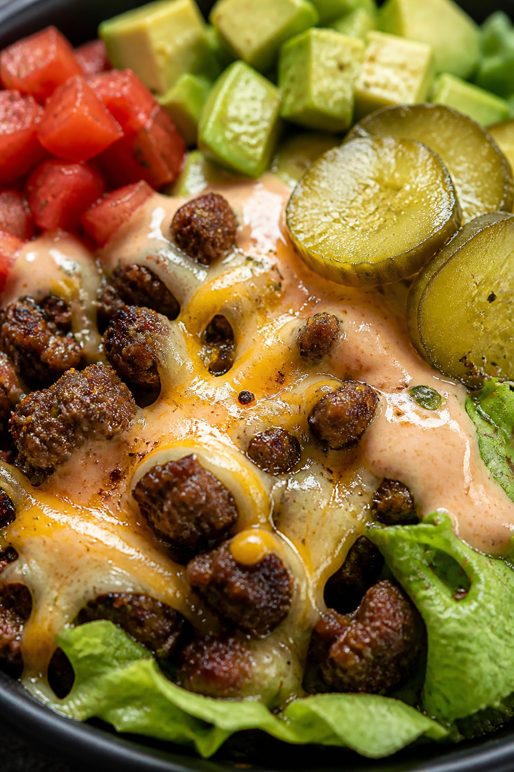 Close-up final detail: Ultra-close shot of a greens-based Cheeseburger Protein Bowl showing juicy be