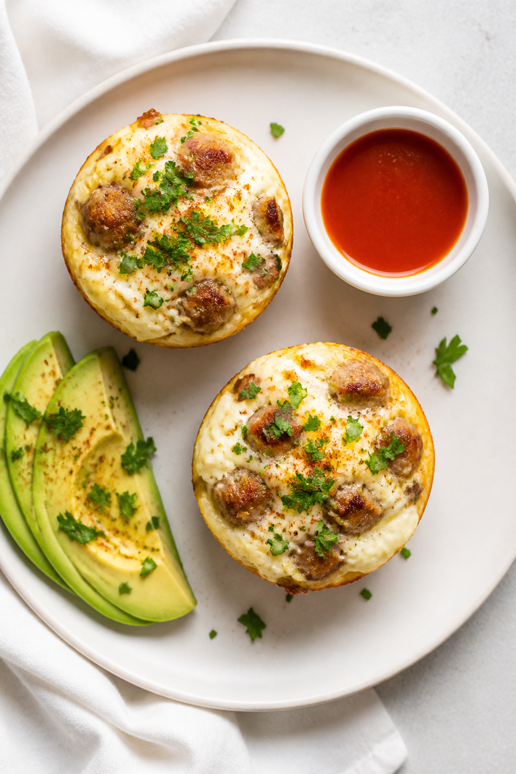 Final dish, top view: Overhead shot of two egg white & turkey sausage muffins on a matte white plate