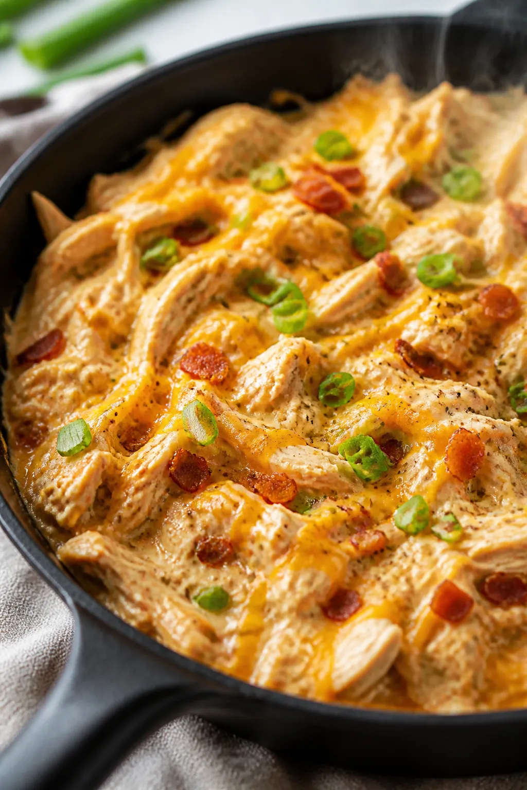 Close-up detail: Creamy shredded crack chicken in a skillet, strands of tender chicken coated in a g