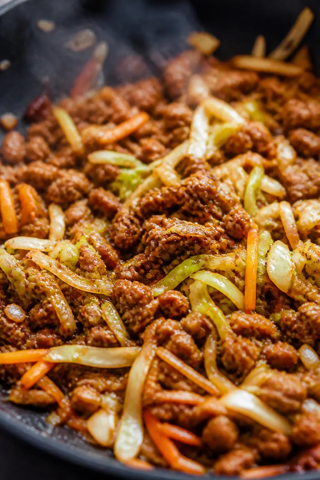 Close-up detail: Ground chicken crumbles sizzling in a large skillet, lightly browned with glossy ed