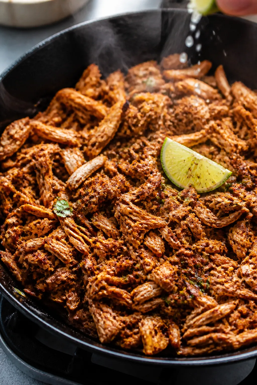Cooking process: Skillet close-up of shredded rotisserie chicken sizzling with street taco seasoning
